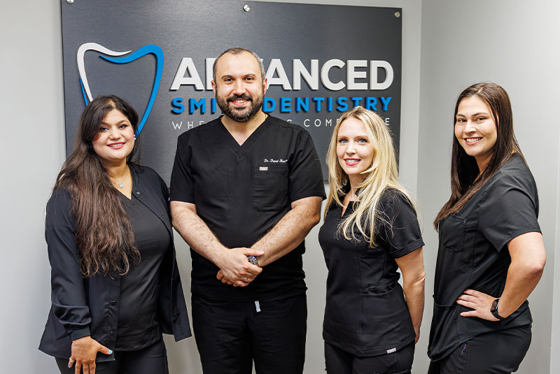 staff members and doctor smiling within the dental center